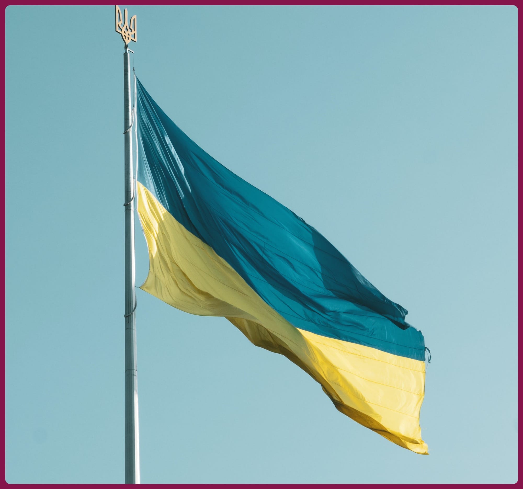 a flag flying in the wind with a blue sky in the background